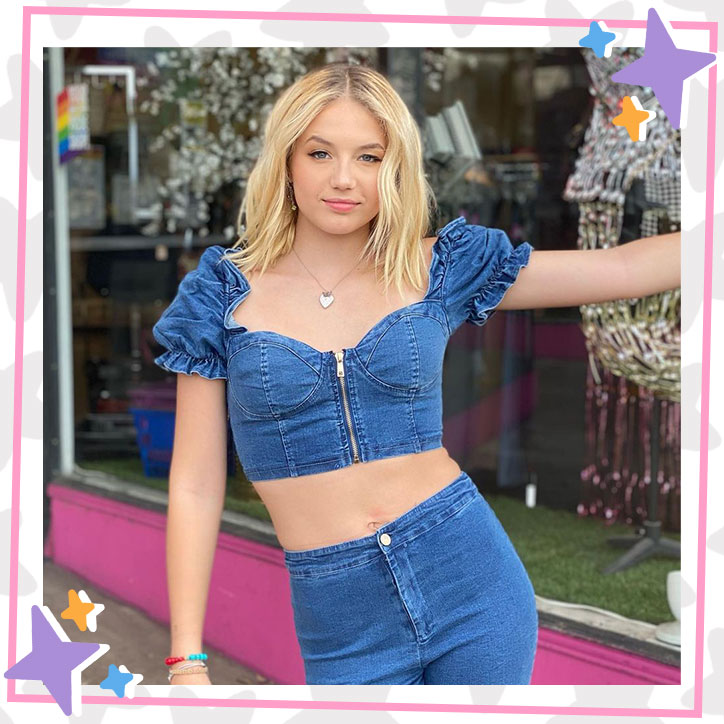 Indi Star posts outside a storefront while wearing a denim croptop with ruffle sleeves