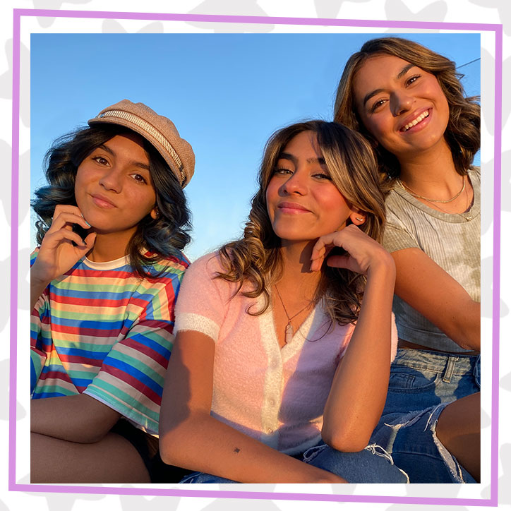 GEM Sisters Evangeline, Mercedes, and Giselle sitting together outdoors during a sunset