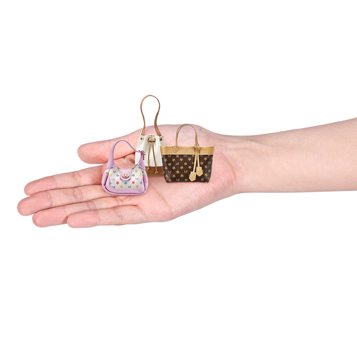 A hand holding out three mini-sized handbags from ZURU's 5 Surprise Mini Fashion collectibles line