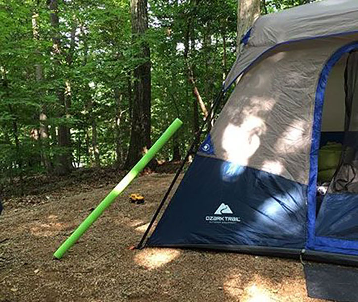 Photo of a tent set up in the woods using poodle noodles over the guy lines to make them more visible