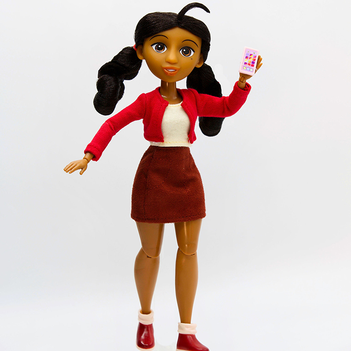 The Penny Proud fashion doll stands in her signature outfit from the animated series, posed holding a smartphone