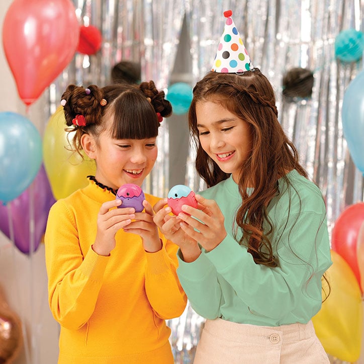 Two tween girls dressed for a birthday party playing with their Tamagotchi Pix Party devices