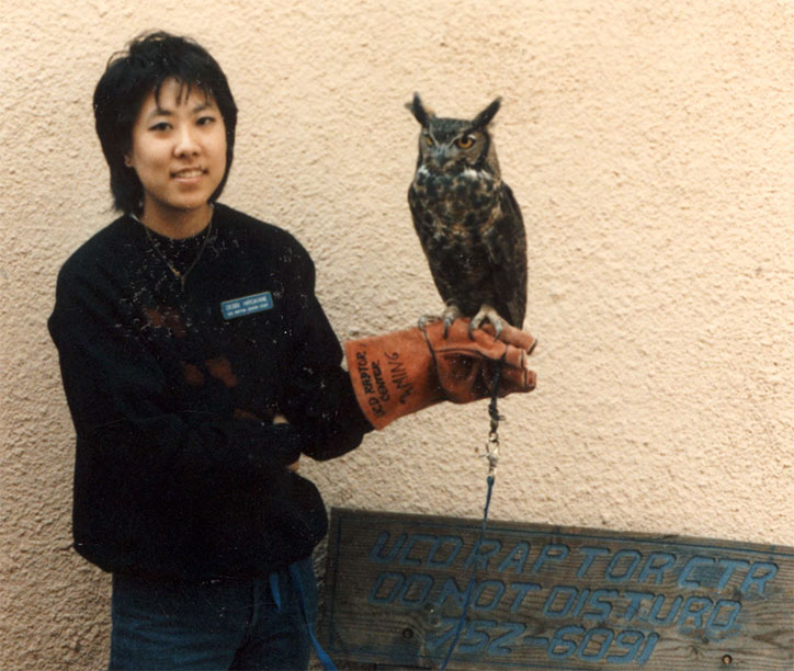 College aged Debbi Michiko Florence holds an owl on a gloved hand at a bird sanctuary.