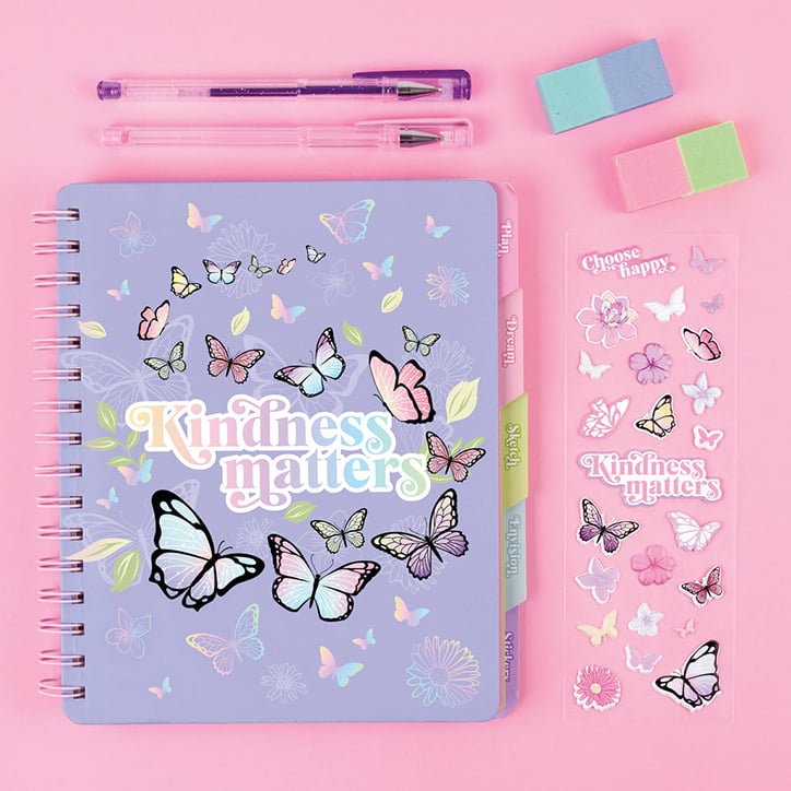 Flat lay of the 3C4G Butterfly Deluxe Journaling Set including lavender journal with the words "kindness matters" on the front, surrounded by butterflies, erasers, gel pens, and sticker sheet.