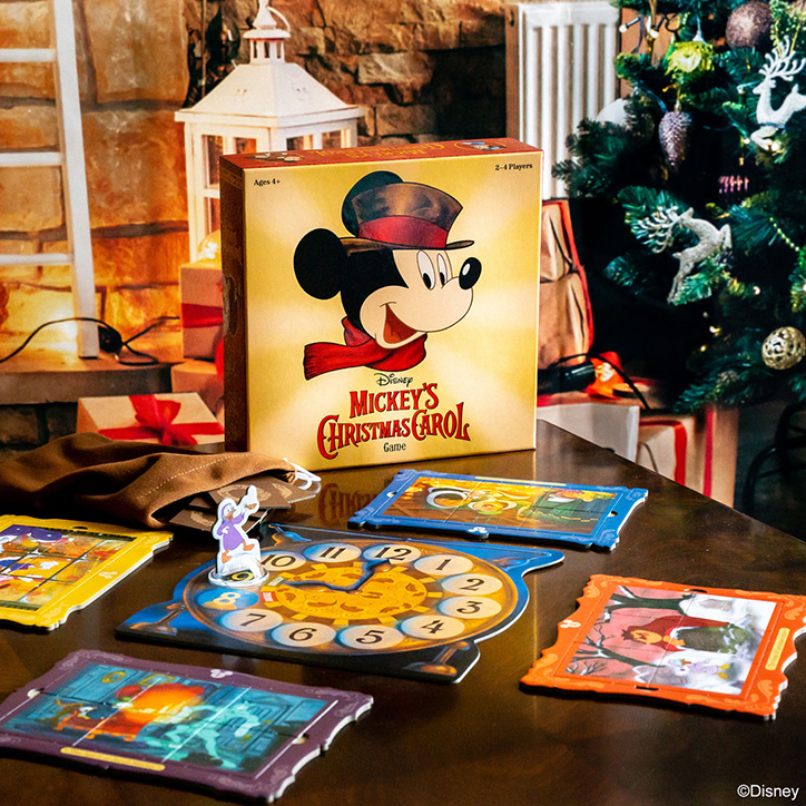 Lifestyle photo of the Disney Mickey's Christmas Carol game laid out on a table in a living room decorated for the holidays