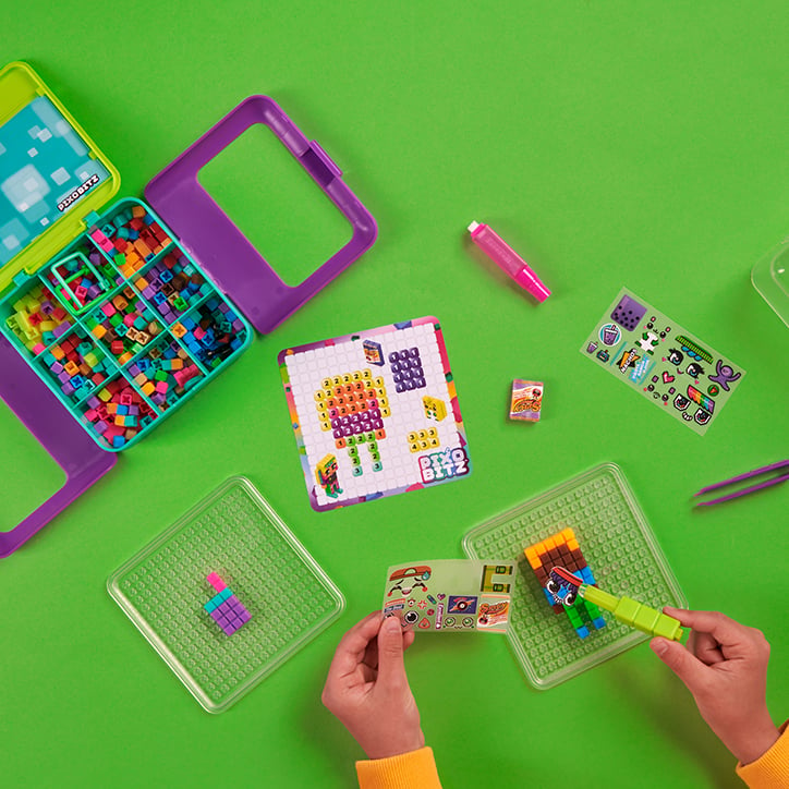 Flat lay of the Pixobitz Studio kit, showing colorful Bitz in the storage case and a Pixobitz creation being designed on the tray