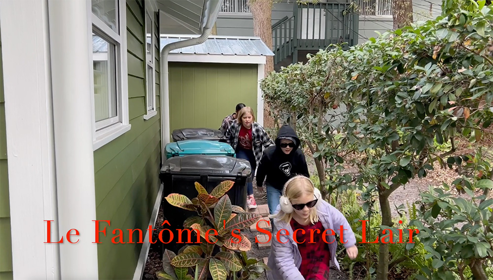 Four kids walking alongside the side of a house. There is a text overlay that reads "Le Fantôme's Secret Lair"